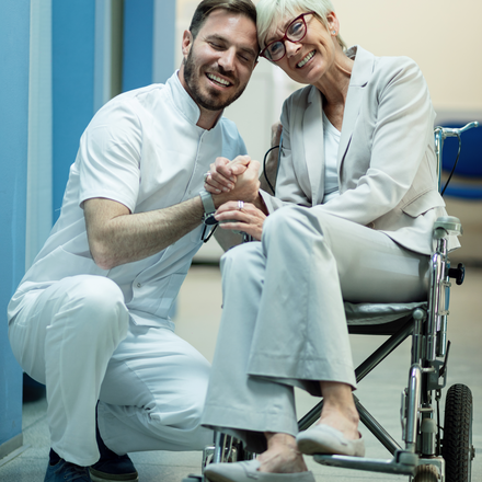 happy-mature-woman-wheelchair-holding-hands-with-her-doctor-hospital-hallway.jpg